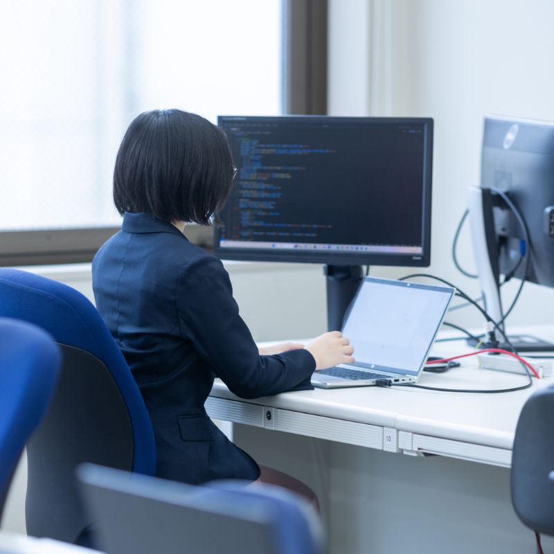 パソコンに向かって仕事をする女性の後ろ姿